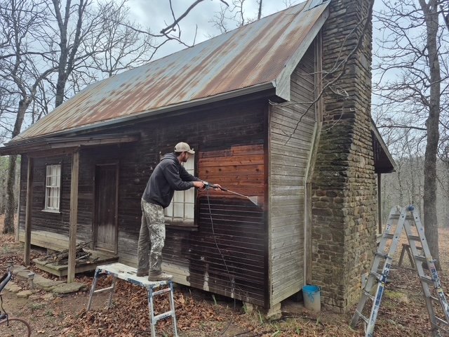 Cabin chimney side being pressure-washed, weathered wood