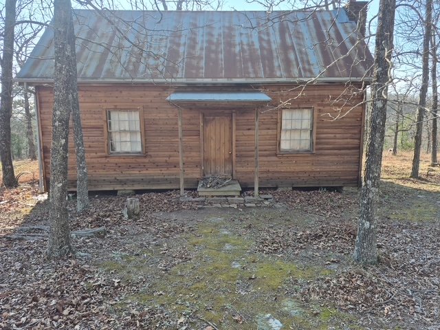 Restored log cabin front with metal roof
