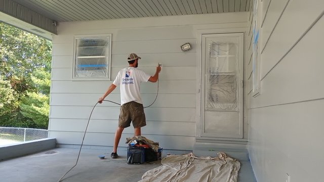 Spraying exterior siding on a covered patio